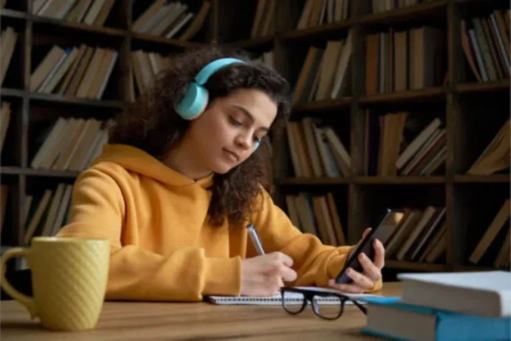 Uma mulher com o smartphone na mão estudando.