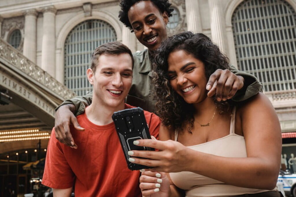 Três pessoas vendo um conteúdo no smartphone.