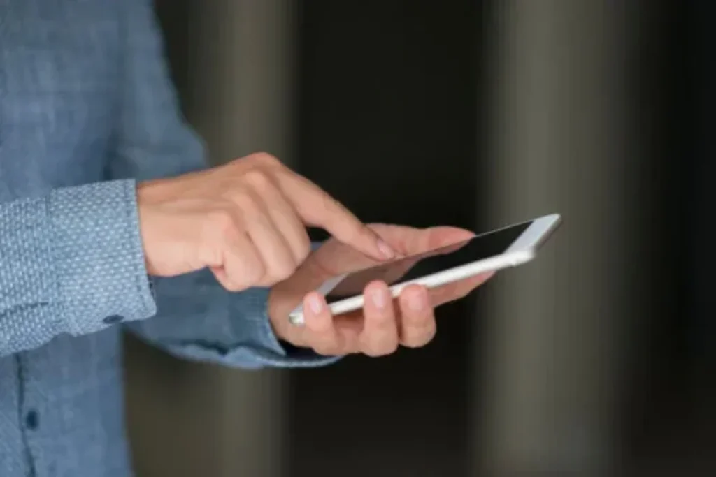 Uma pessoa clicando na tela de um smartphone simples. 