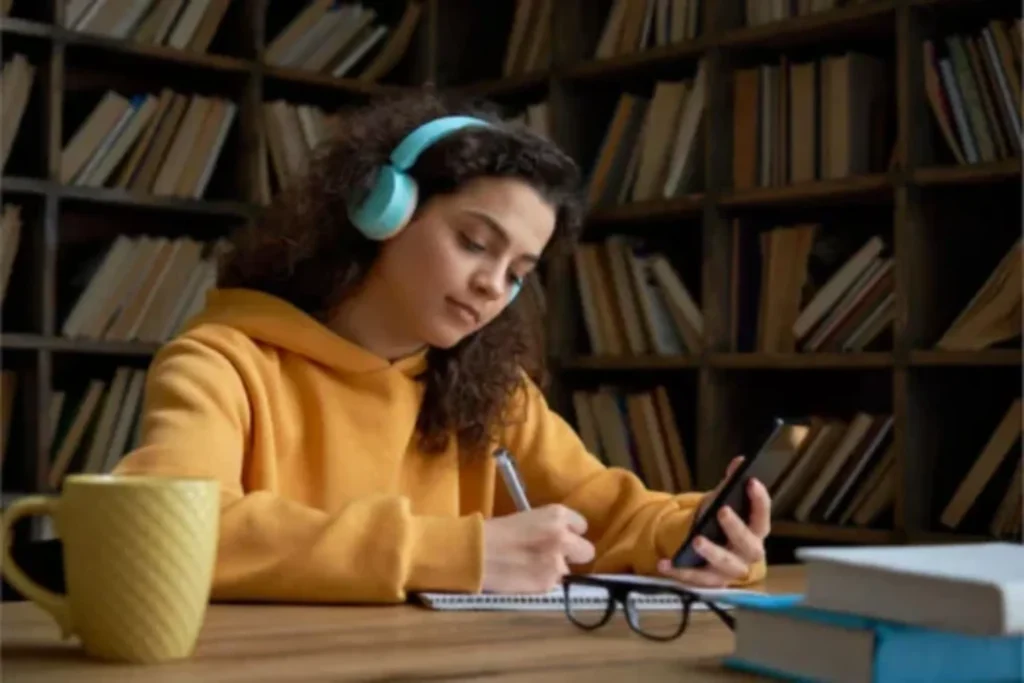 Uma pessoa estudando com um smartphone na mão. 